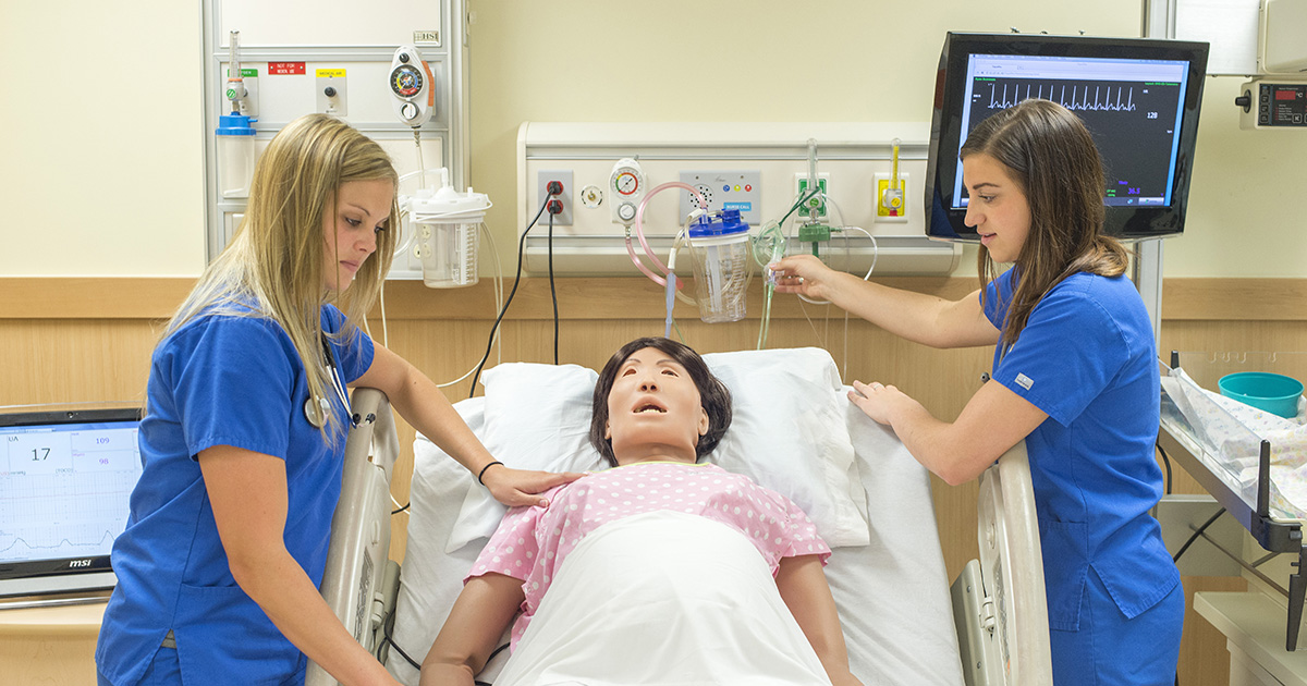 Nursing students work with a manikin patient in a sim lab.