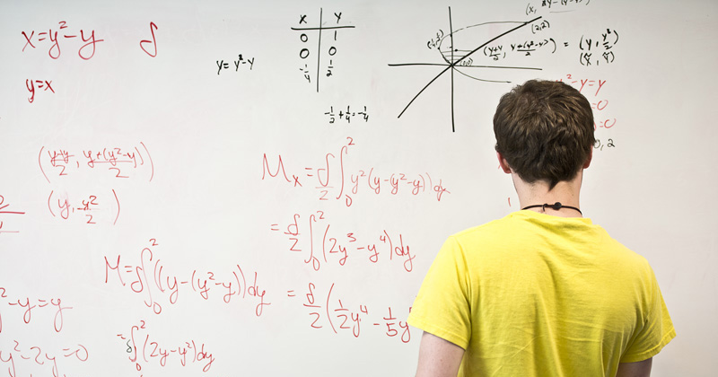 A math student works on a whiteboard.