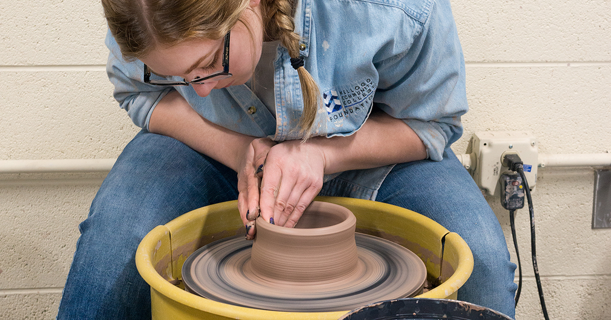 A Ceramics student makes a pot on a wheel.