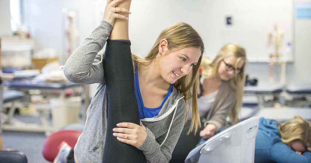Students practice stretching techniques on other students.