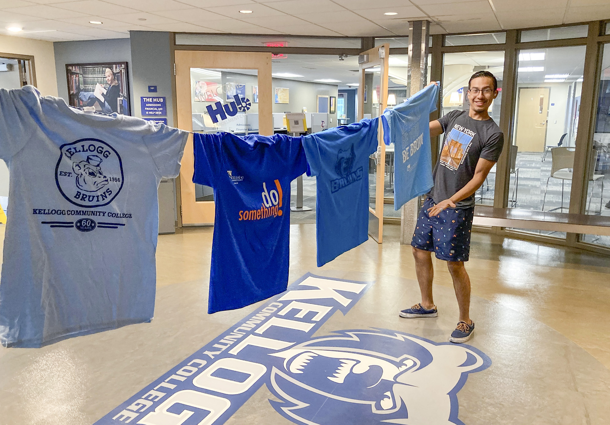 A student poses with four blue T-shirts strung on a line.