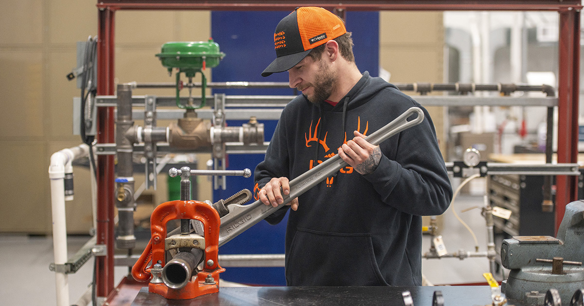 A Pipefitting students uses a wrench in the lab.
